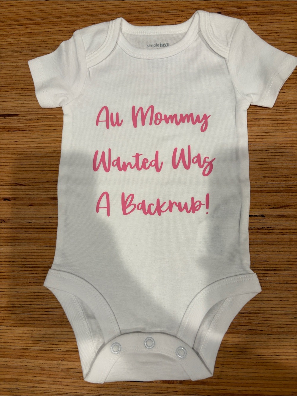 Simple White One-Piece with Pink Script Saying "All Mommy Wanted Was A Backrub!"